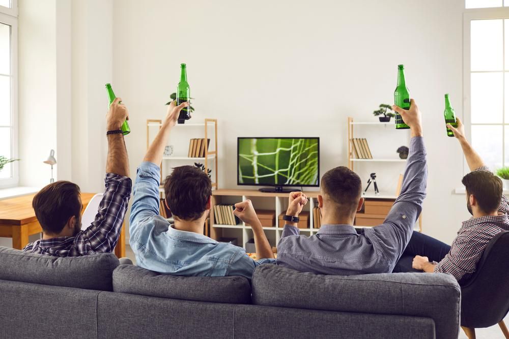Fiatal férfiak meccset néznek a nappaliban sörrel