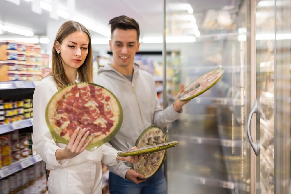 Élelmiszerüzletben két fiatal fagyasztott pizzákat válogat
