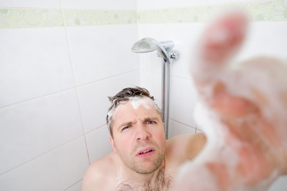 Zuhanyzó férfi rejtett kamerába néz