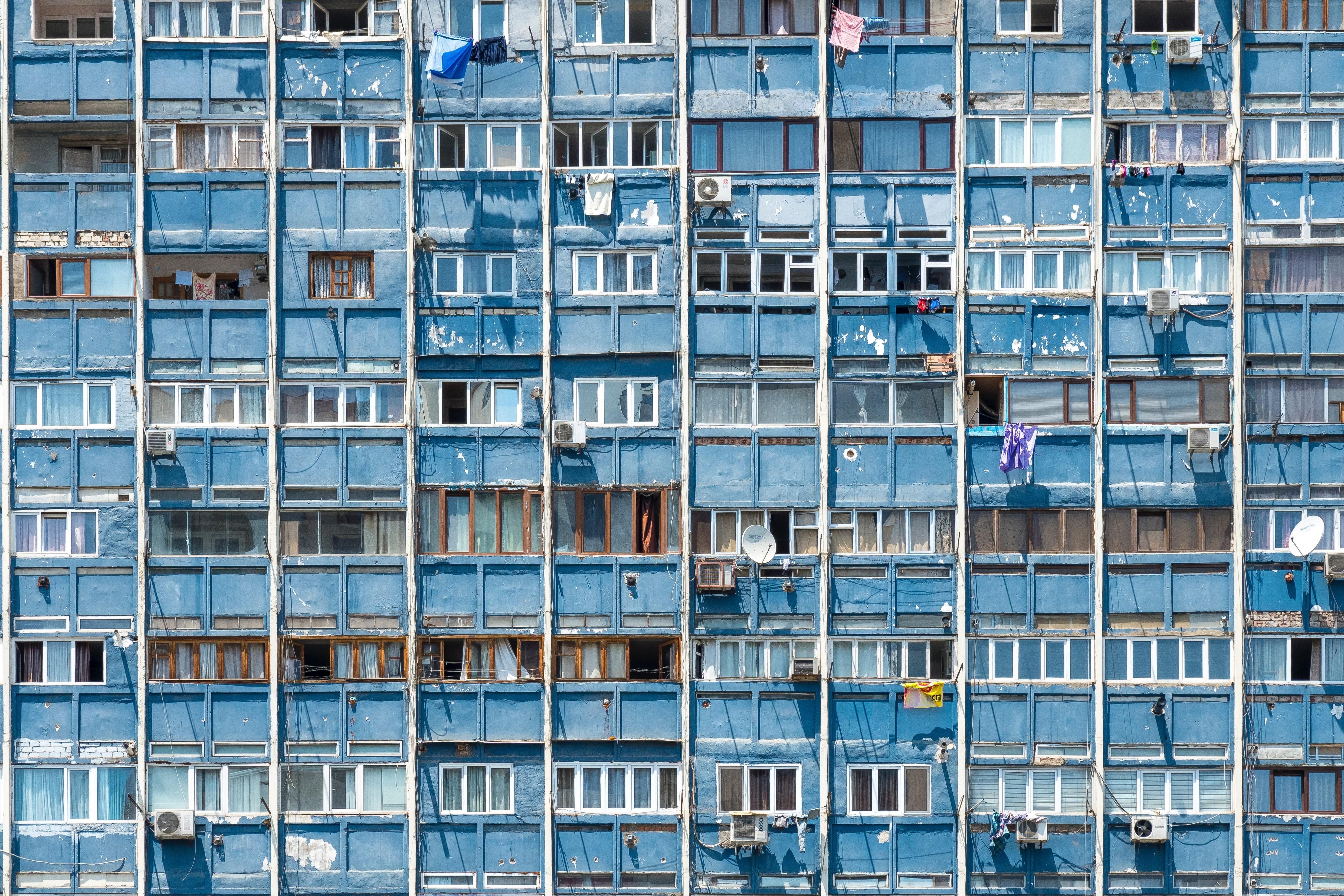 Zsúfolt lakótelepi ház kék színű homlokzata