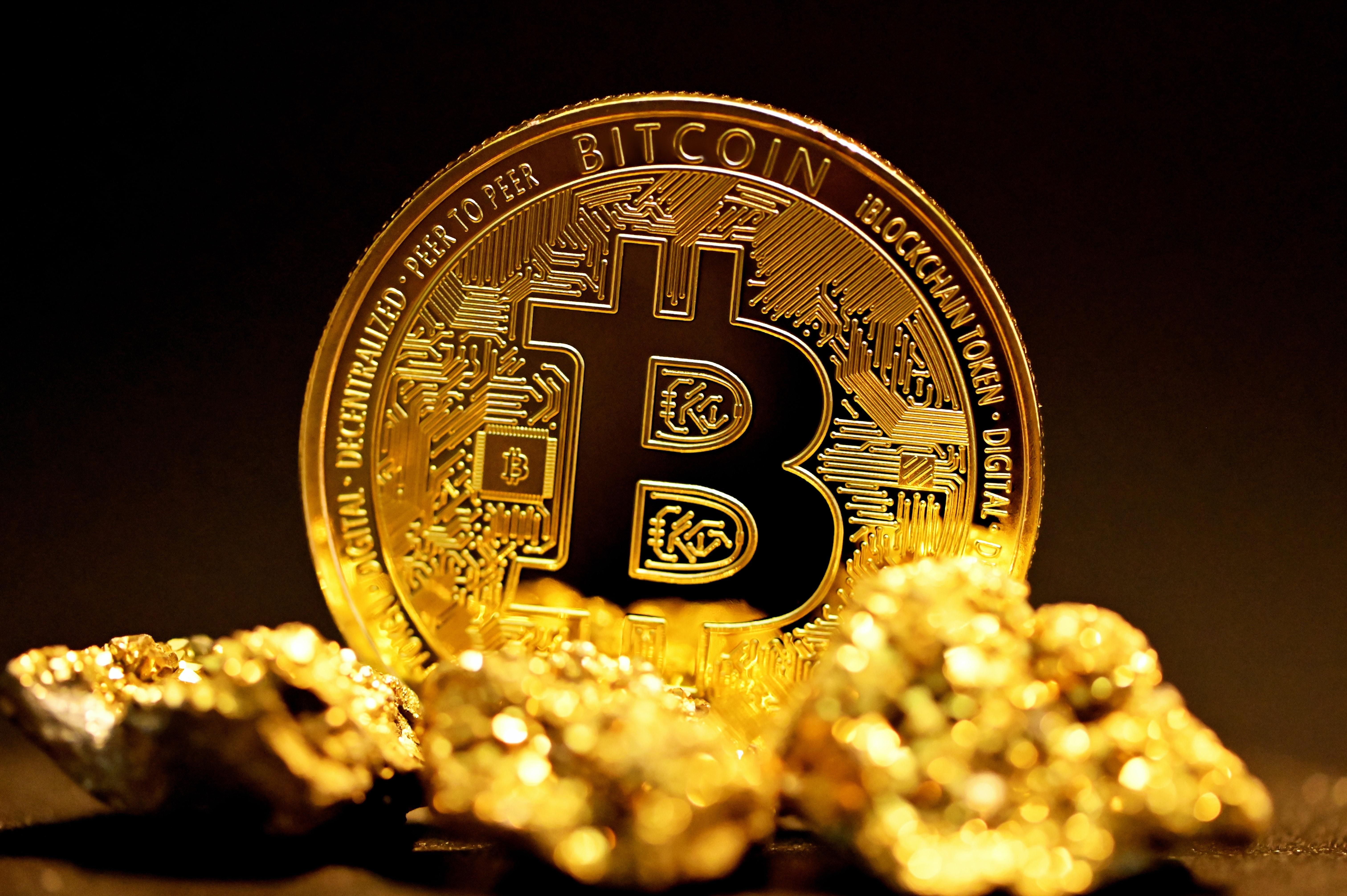 Bitcoin érme előtte aranyrögökkel