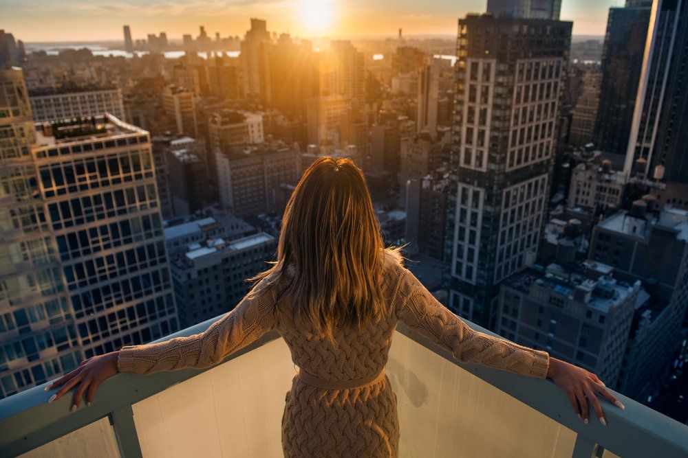 Tehetős nő élvezi a naplementét New Yorkban egy teraszon