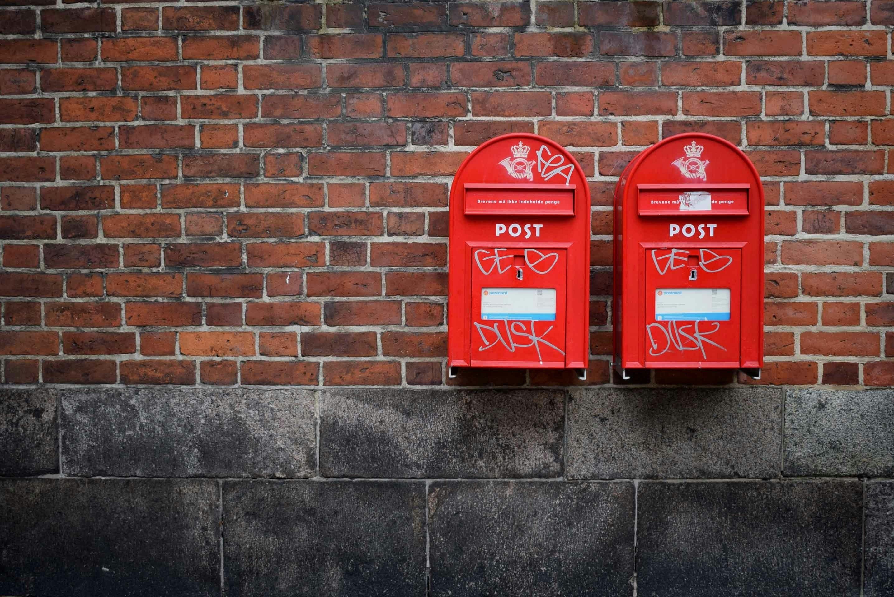 Két piros postaláda egy téglafalon