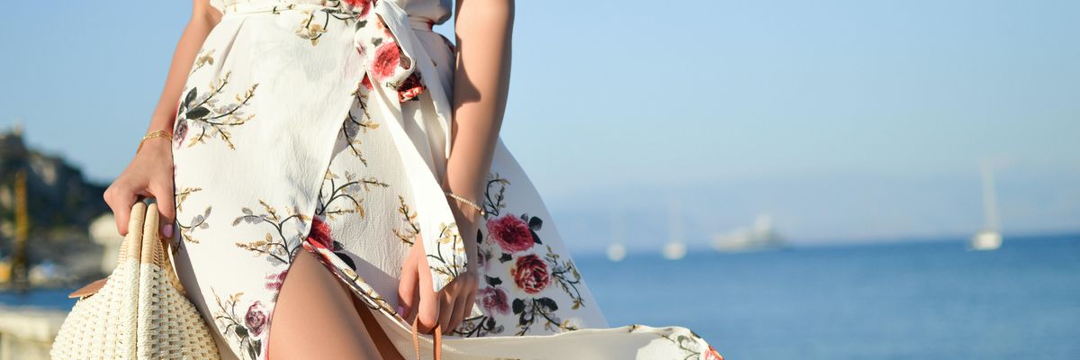 Influenszer nyári ruhában táskával napsütésben egy tengerparton