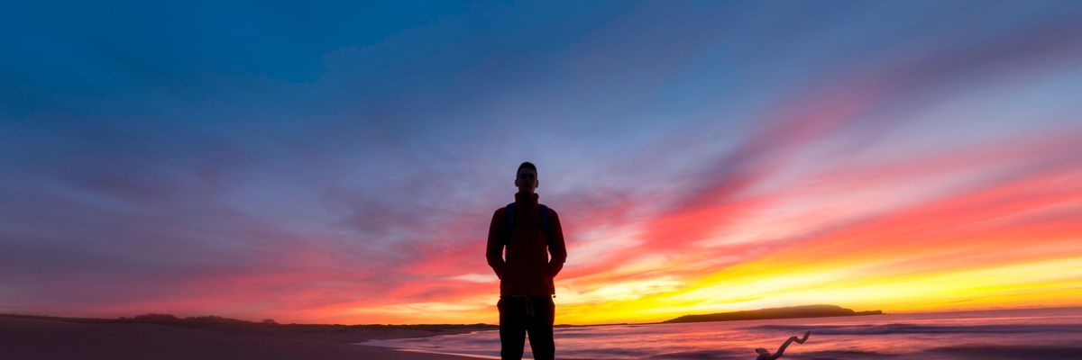 Introvertált ember áll a tengerparton naplementében