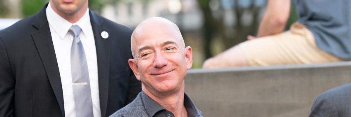 Jeff Bezos mosolyogva nézi új szuperjachtját szürke öltönyben