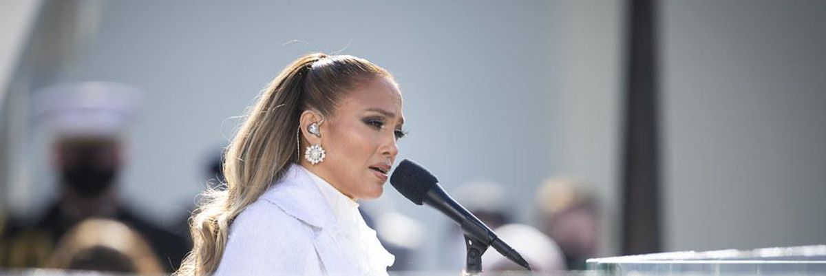 Jennifer Lopez fehér ruhában énekel a színpadon egy mikrofonba