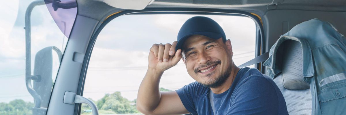 Jól kereső angliai kamionsofőr mosolyog a volánnál