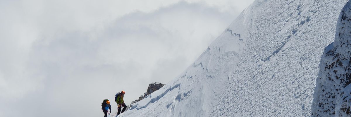 Két hegymászó egy meredek hegyoldal aljából felfelé indul