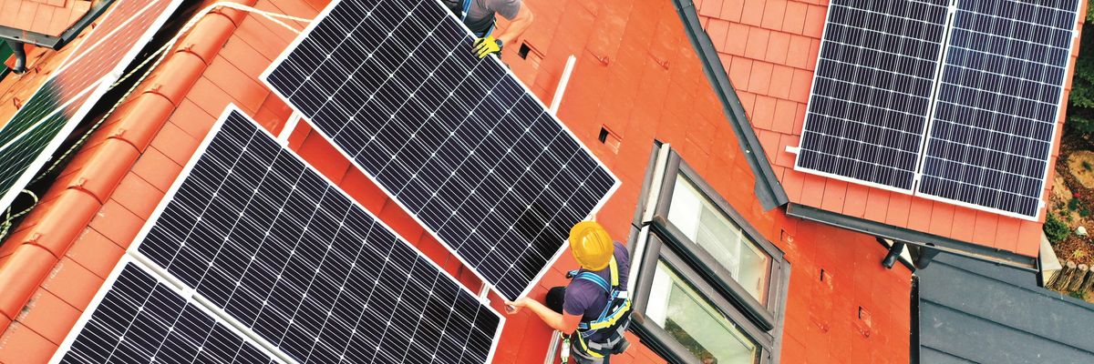 Két munkás napelemet szerel egy tetőre