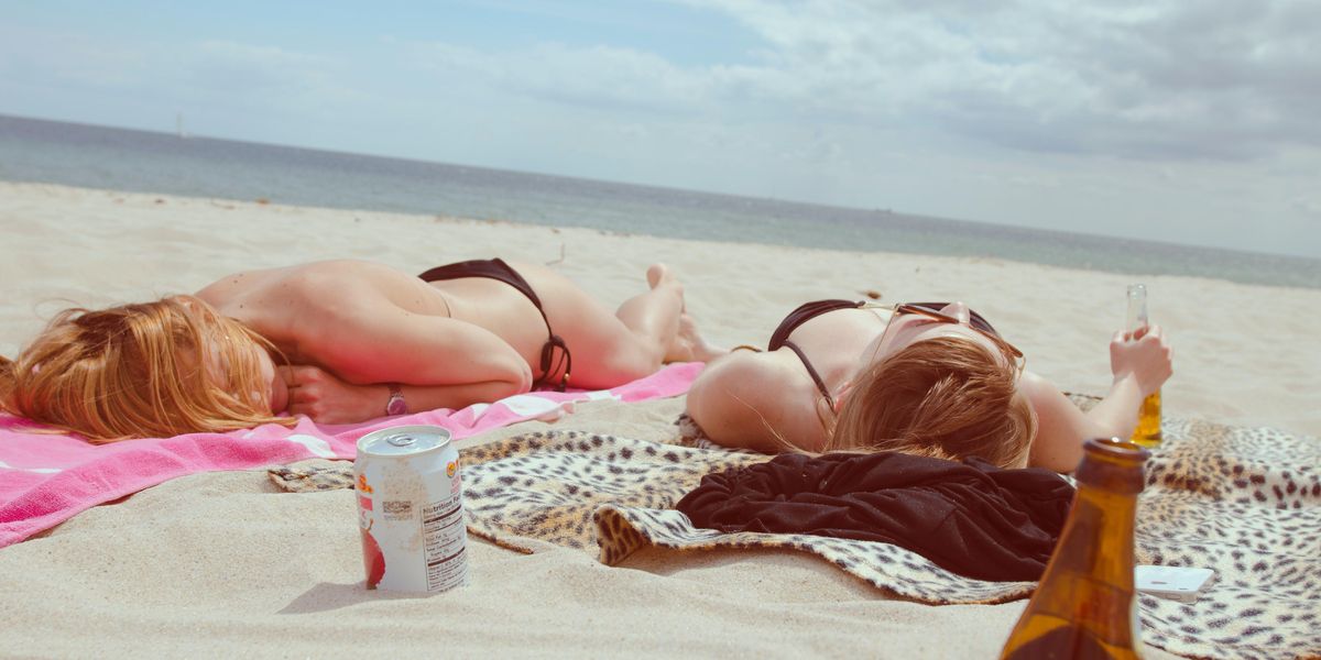 Két nő a homokos tengerparton napozik