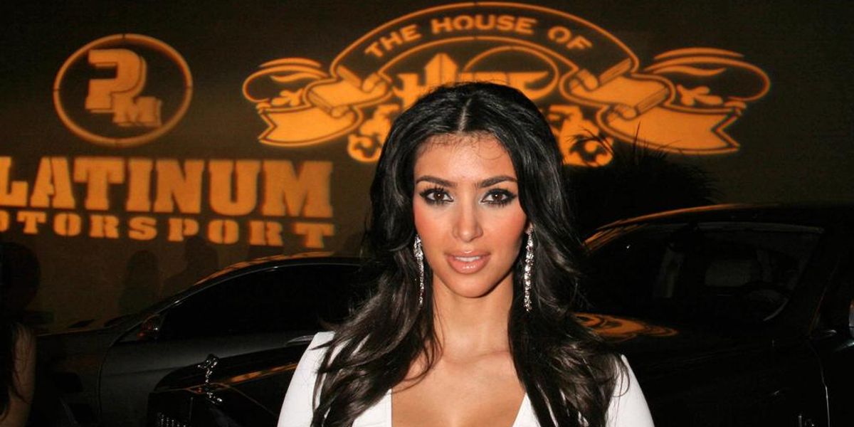Kim Kardashian egy Rolls-Royce előtt áll egy  mélyen dekoltált fehér felsőben