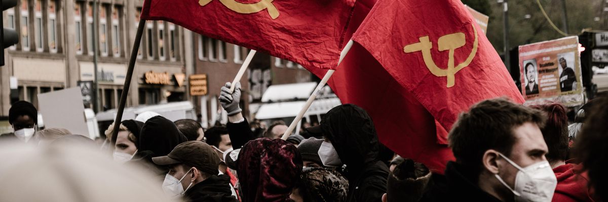 Kommunista zászlókat lengetnek emberek az utcán
