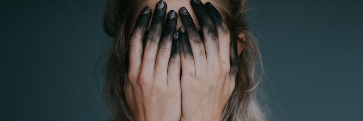 Kormos ujjakkal arcát eltakaró meztelen nő