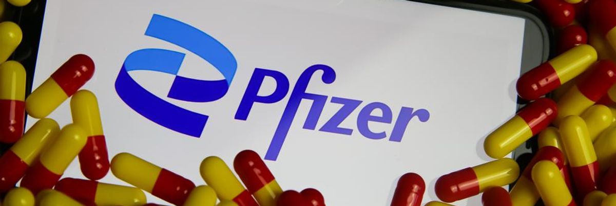 Koronavírus elleni, sárga-piros gyógyszerekkel körülvett okostelefon, melynek képernyőjén a Pfizer logója látható