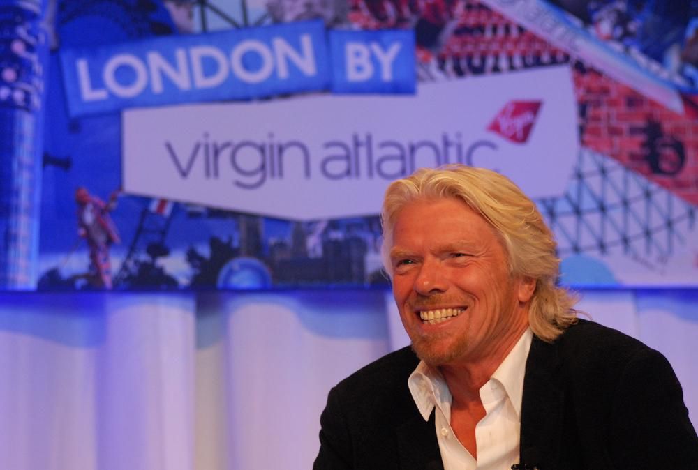 Richard Branson mosolyog, lila háttérrel