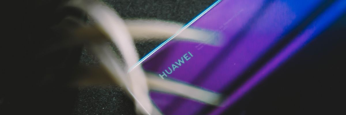 Lila színű Huawei telefon képernyővel lefelé egy növény mellett