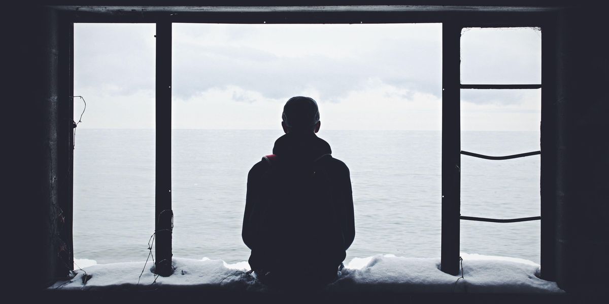 Magányos férfi ül egy behavazott ablakban a tengert bámulva