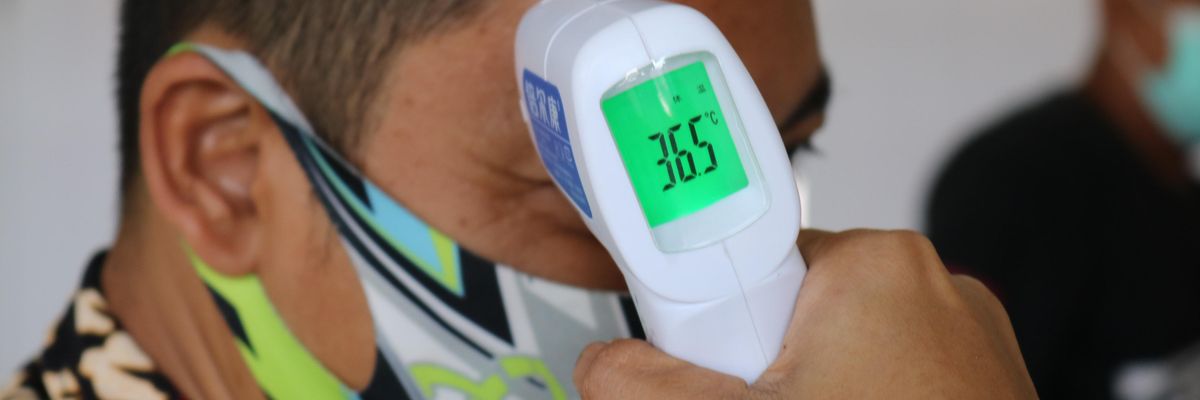 Maszkos Amazon dolgozó testhőmérsékletét ellenőrzik hőmérséklet ellenőrző piztollyal