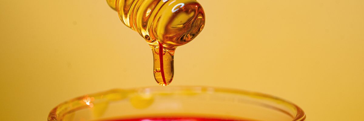 Mézes üvegbe cseppenő méz