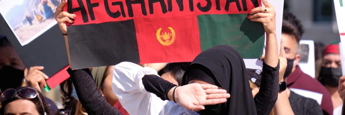 Nők tiltakoznak Afganisztánban, miután Kabult elfoglalták a tálibok, az egyik nő "Save Afghanistan" feliratú táblát tart a kezében