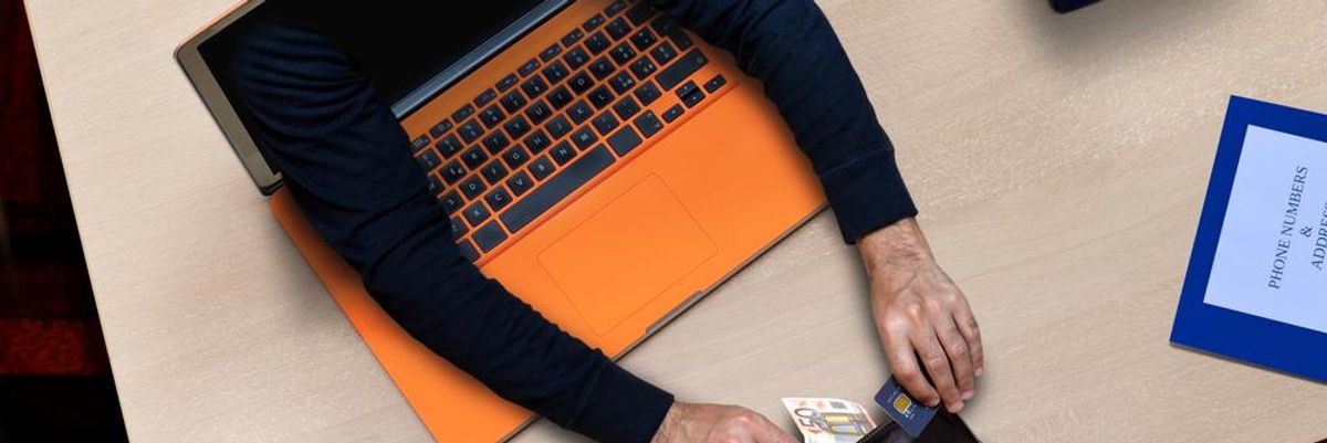 Online csaló kinyúl a narancssárga laptop képernyőjéből és ellopja a felhasználó pénzét és bankkártyáját