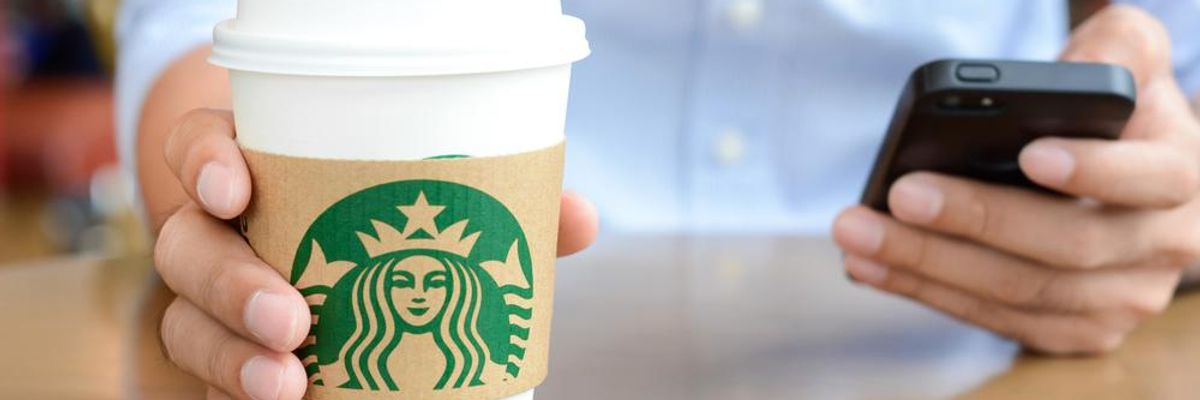 Starbucks logó egy papírpoháron, okostelefon