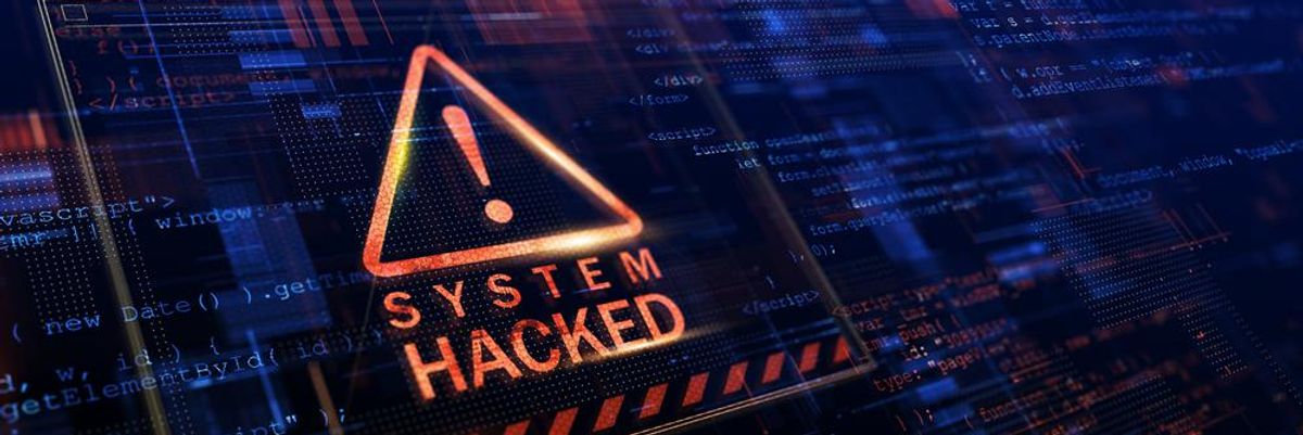 System hacked, azaz "meghackelték a rendszert" felirat egy háromszögben lévő felkiáltójel alatt, ami mögött magas szintű programkódok futnak