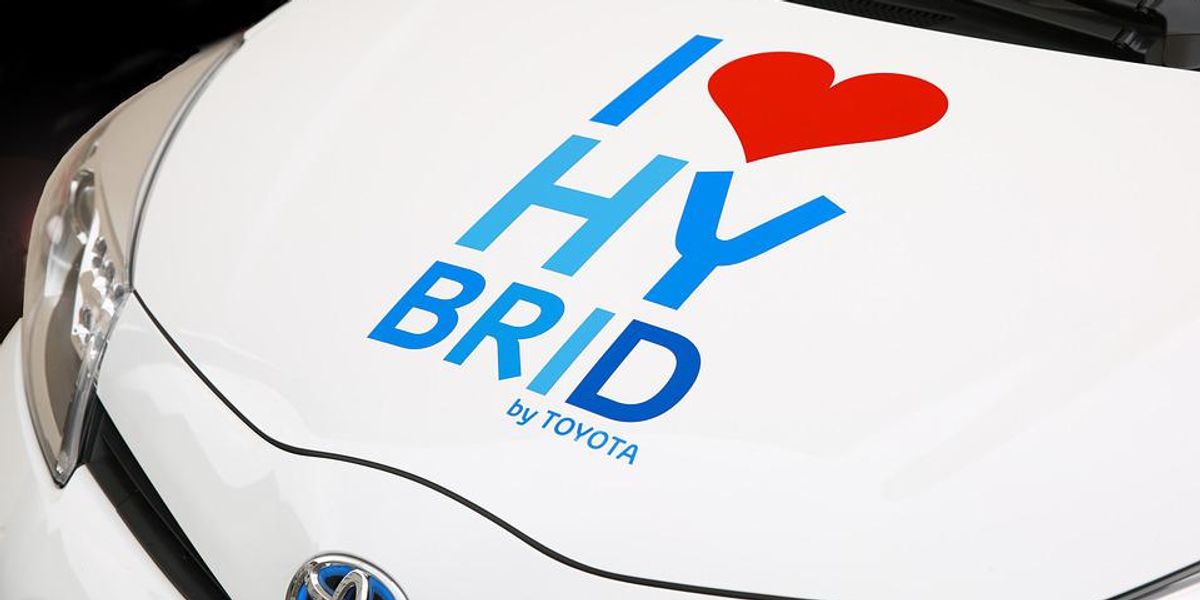 Szeretem a hibridet felirat egy fehér Toyota hibrid meghajtású autó motorháztetőjén