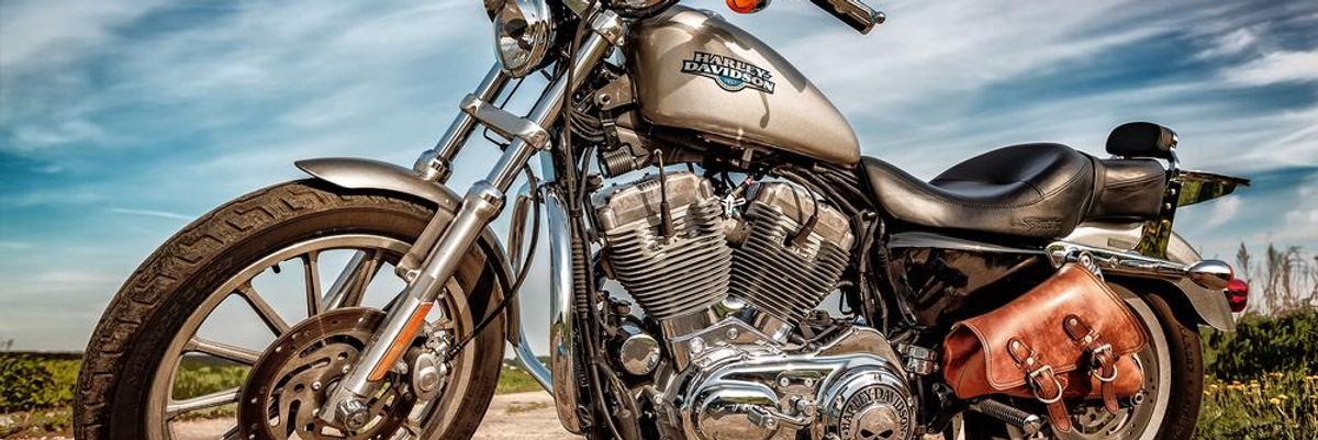 Szürke színű Harley-Davidson kitámasztva egy út közepén, napos időben