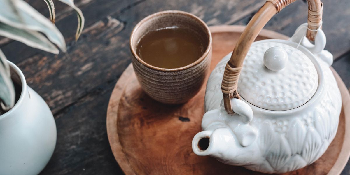 Tea egy csészében, teáskanna mellett, faasztalon