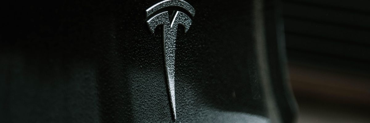 Tesla autó logoja közelről vízpermettel fedve