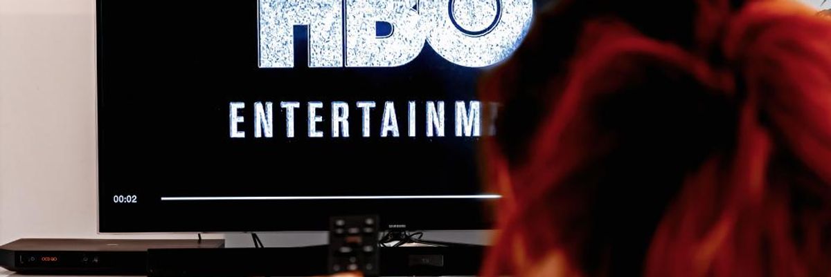 Vörös hajú nő távirányítóval a kezében arra készül, hogy az HBO Entertainment által gyártott Trónok Harca sorozat 4. évadjának 10. részét megnézze